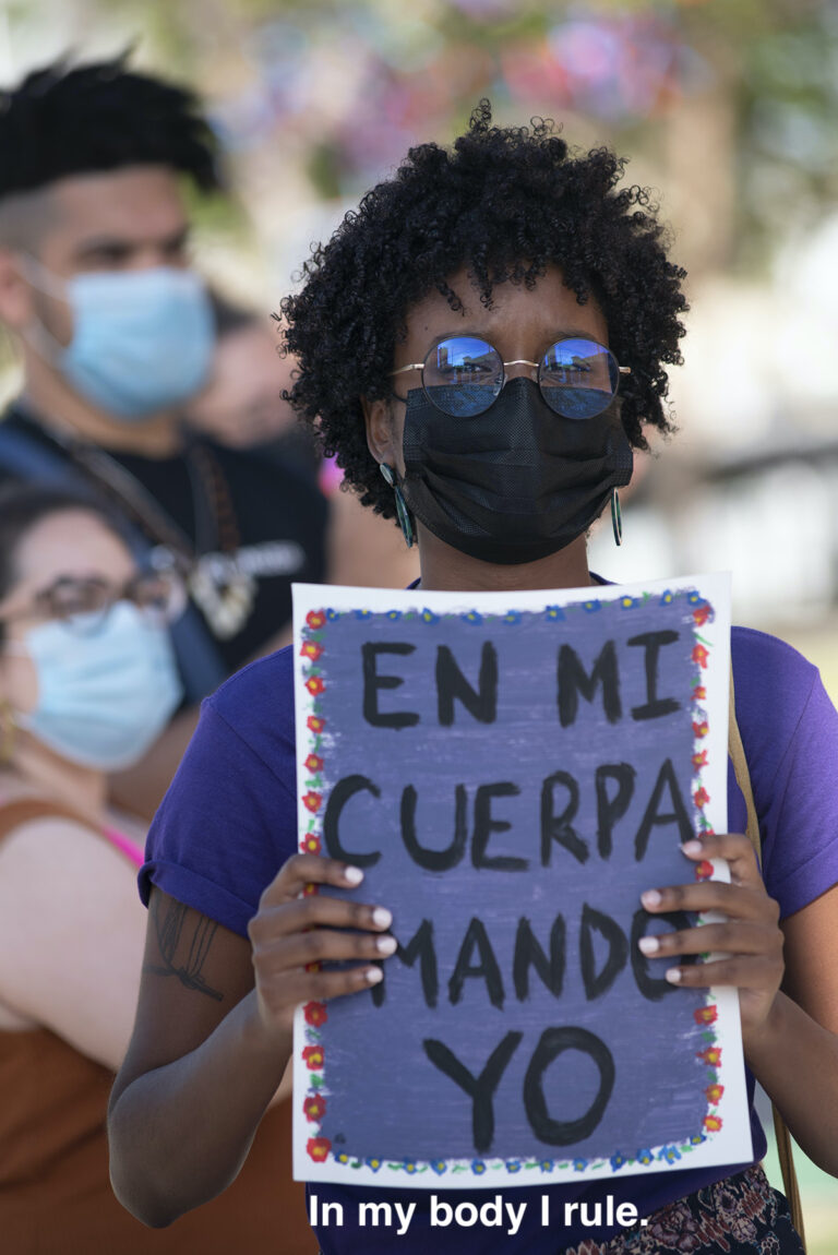 woman holds sign in Spanish Translation: In my body I rule